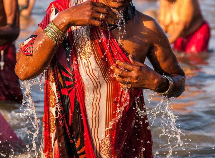 Khumb Mela, mulher com sari vermelho a banhar-se no rio Yamuna