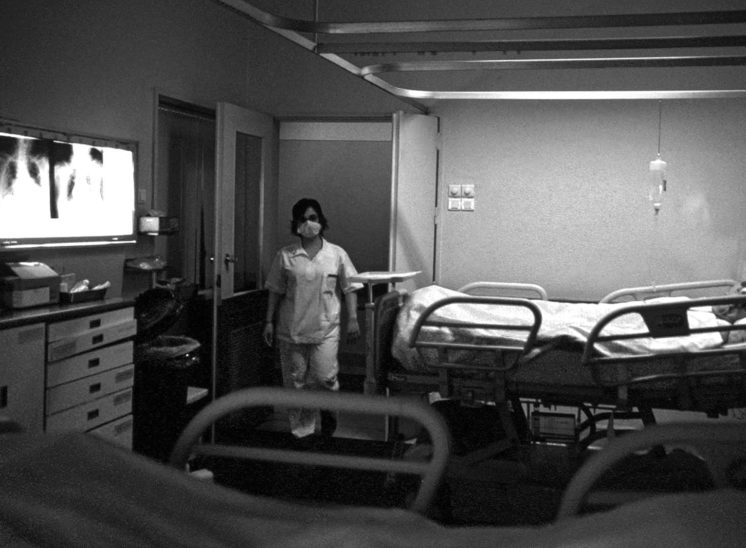 Hospital, enfermeira à entrada de um quarto com doentes