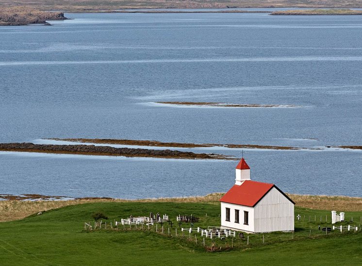 Islândia, casa com telhado vermelho junto ao mar