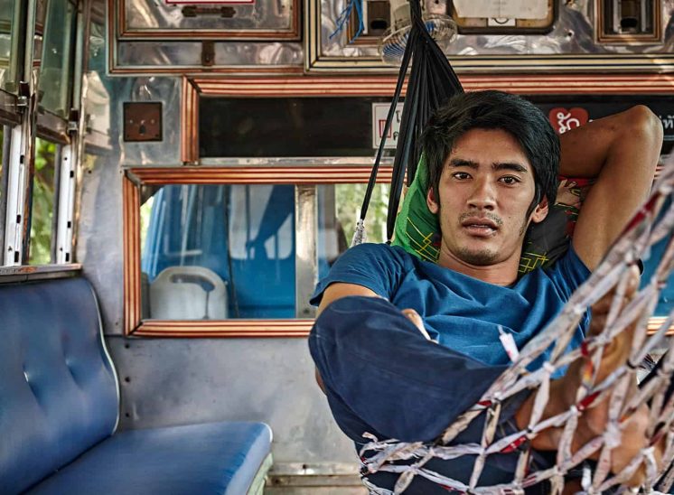 Tailândia, homem deitado numa cama de rede nas traseiras de um Tuk-tuk