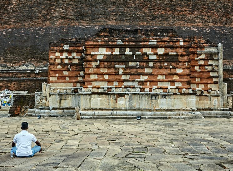 Sri Lanka, homem a meditar em frente a uma grande Stupa