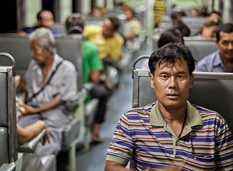 Tailândia, homem olhando para a câmera sentado no interior de um comboio