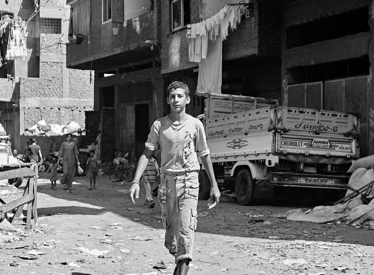 Mokattam Zabbaleen, rapaz a caminhar por entre prédios inacabados