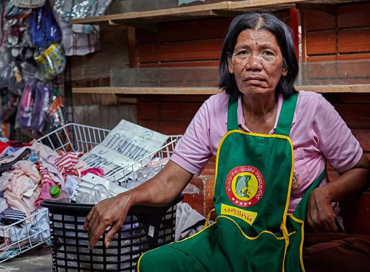 Tailândia, vendedora de têxteis no mercado Samut Songkhram